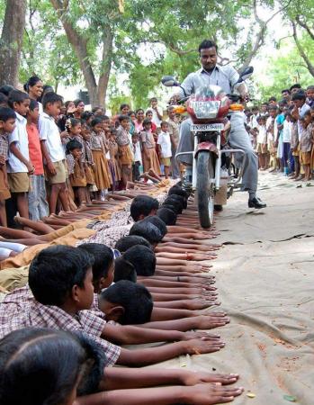 Diretor de escola na Índia pune alunos passando de moto por cima das mãos das crianças
